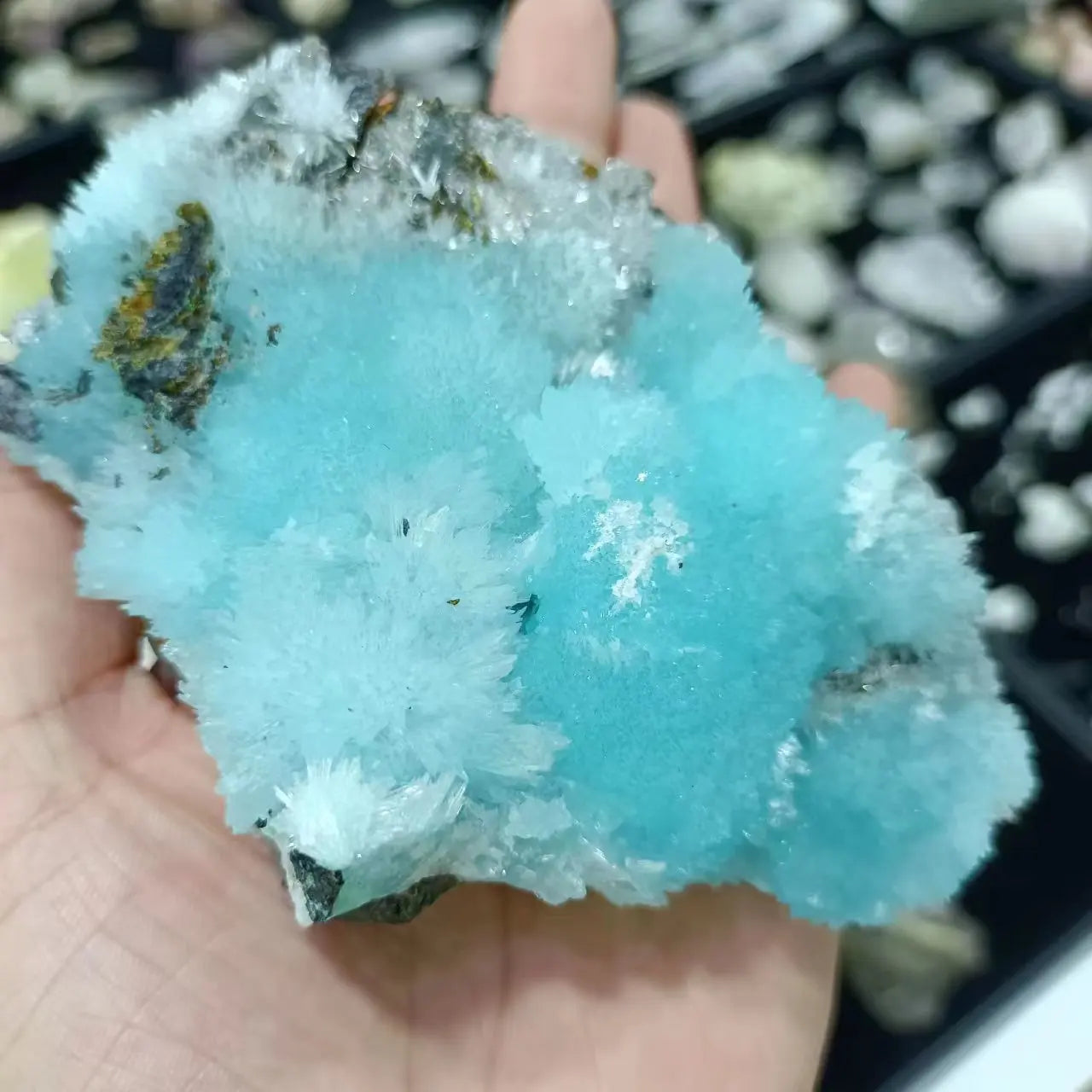 Blue crystal rock held in a hand with a blurred background