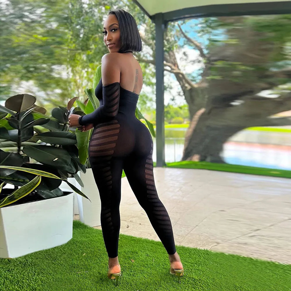 Woman in a black outfit standing outdoors with greenery in the background