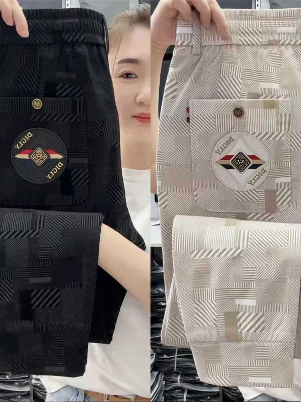 Two pairs of pants, one black and one beige, held up for display with a brand logo visible.
