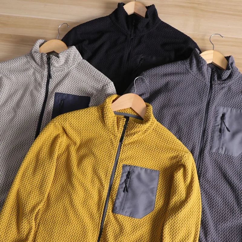 Four jackets in different colors hanging on wooden hangers against a wooden background.