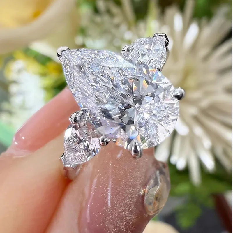 Diamond ring held by a hand with a blurred floral background
