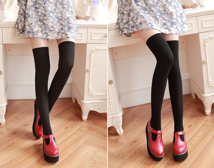 Person wearing black tights and red shoes in a room with wooden floor and white furniture.