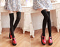 Person wearing black tights and red shoes in a room with wooden floor and white furniture.