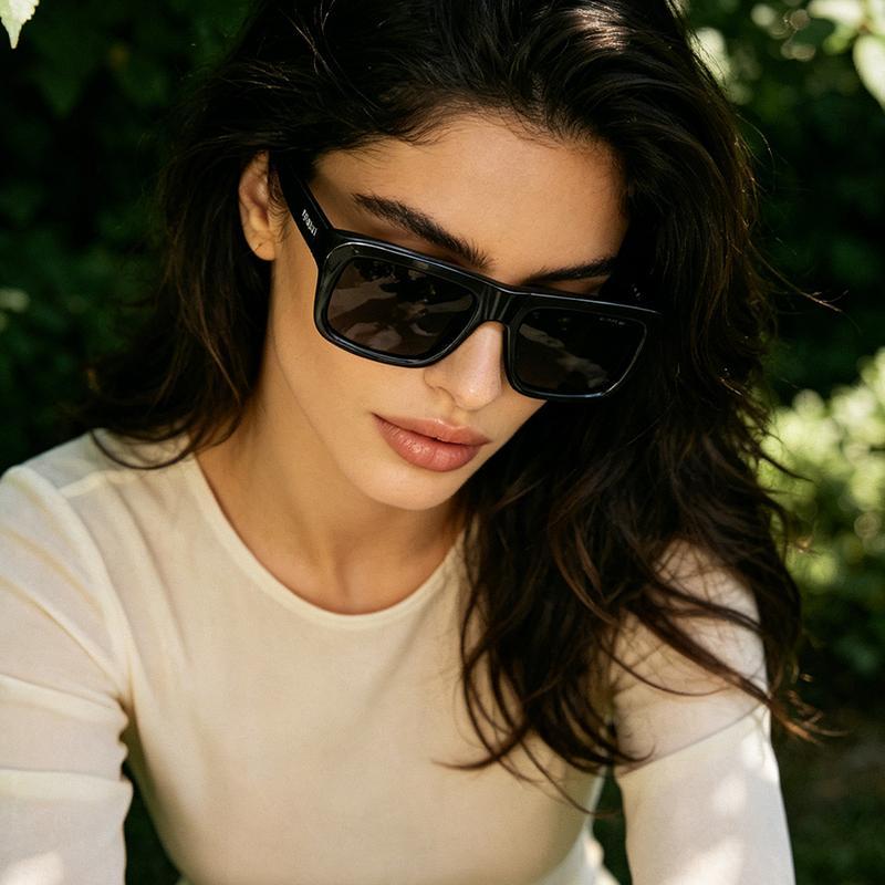 Blonde woman wearing Prada 0PR D11SF sunglasses with Amalfi Coast background