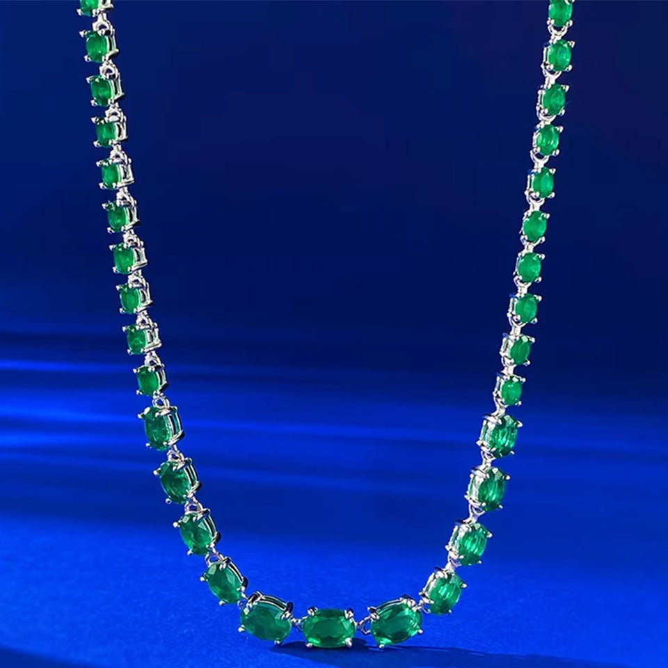 925 Sterling Silver Oval Cut Emerald Tennis Bracelet and Necklace flat lay on blue velvet