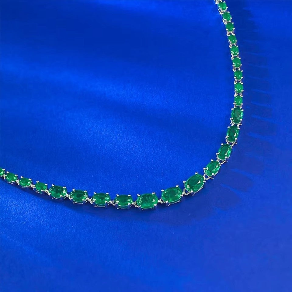 925 Sterling Silver Oval Cut Emerald Tennis Necklace draped in S-curve on blue velvet