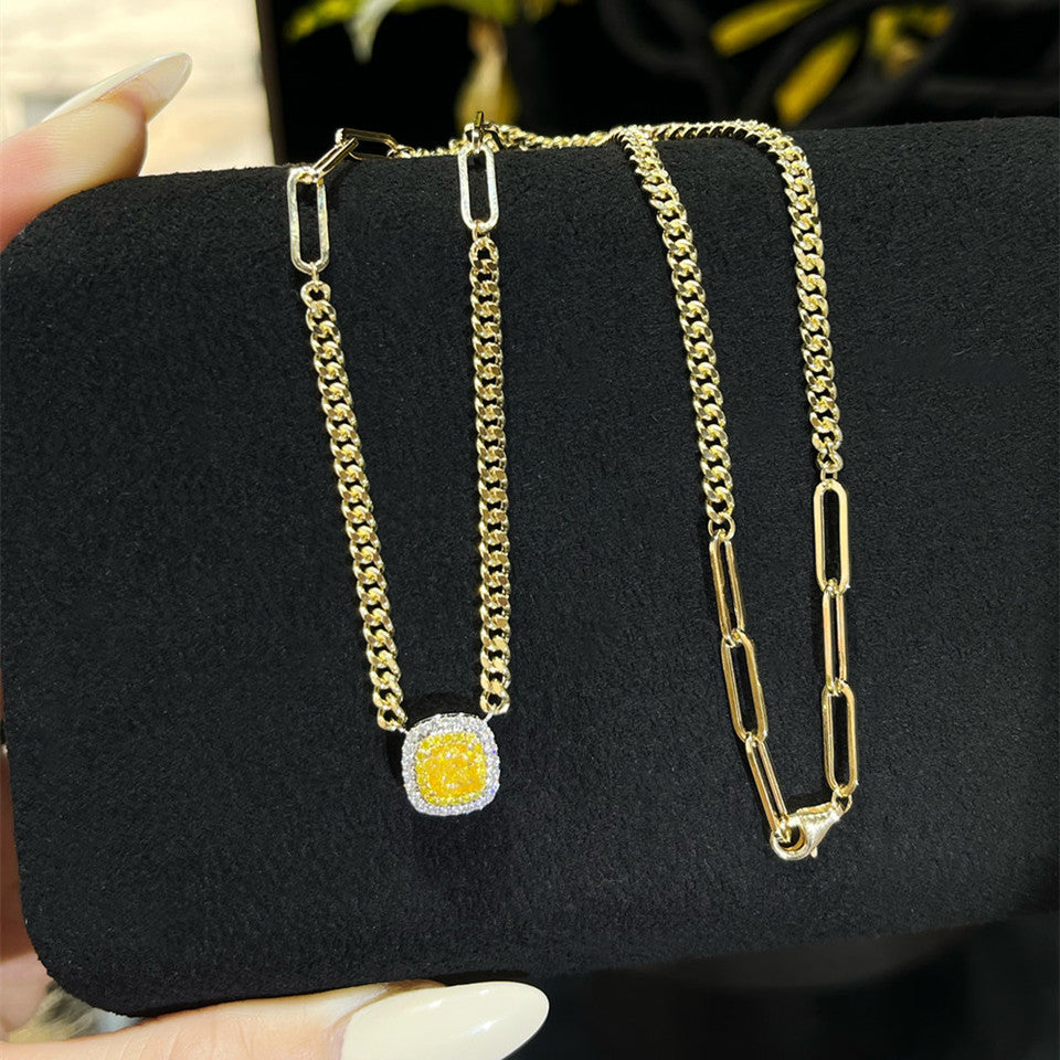 18K yellow gold Cuban link necklace with yellow diamond pendant held on wrist