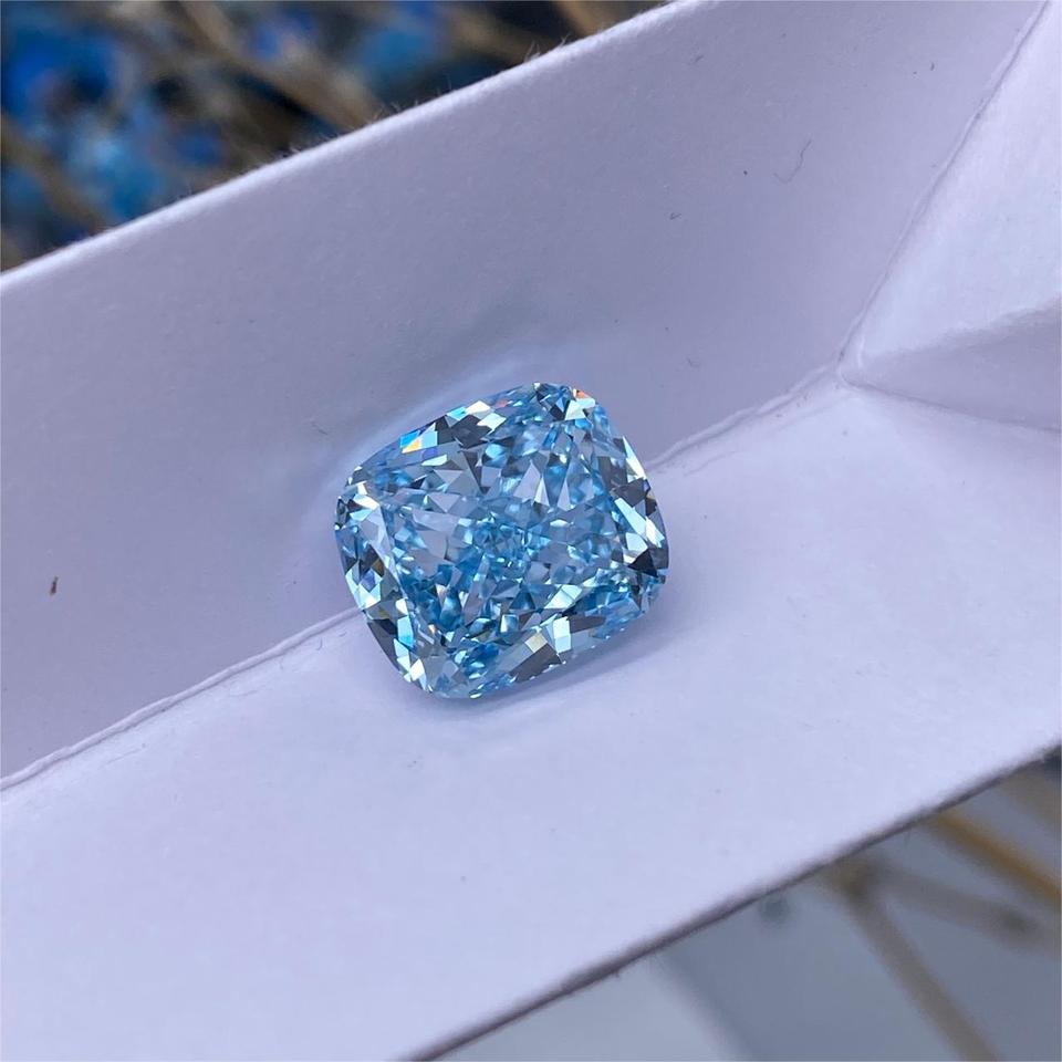 5.83CT Fancy Intense Blue lab-grown cushion cut diamond held between fingers