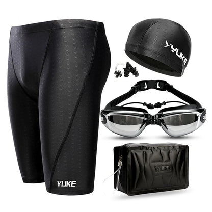 Black swim shorts, cap, goggles, and bag with YUKE branding on a white background