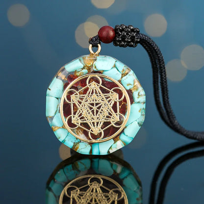 Turquoise pendant with gold geometric design on a black cord against a blue background