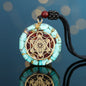 Turquoise pendant with gold geometric design on a black cord against a blue background
