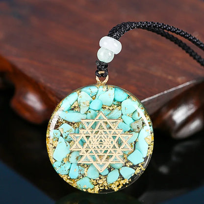 Turquoise stone pendant with gold geometric design on a dark background