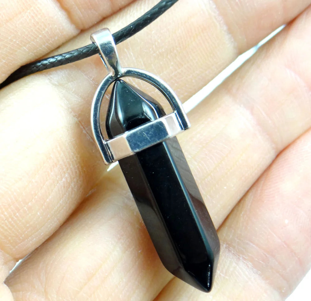 Black pendant on a silver chain held in a hand