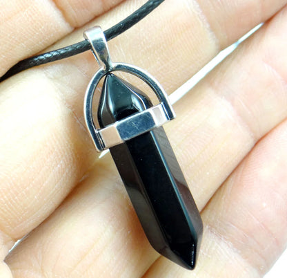 Black pendant on a silver chain held in a hand