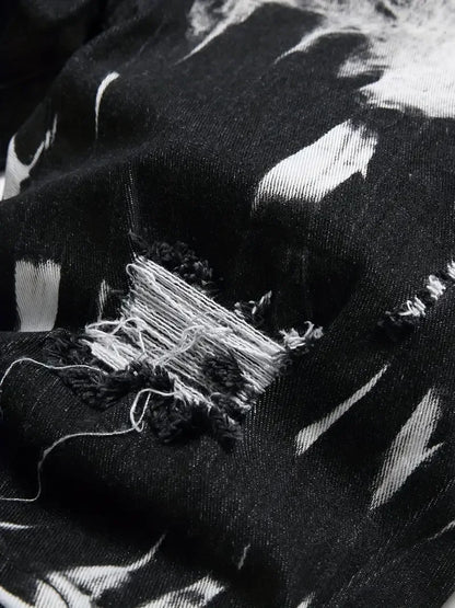 Close-up of a black fabric with white patterns and a tear.