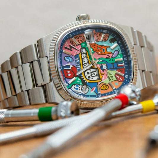 Colorful watch face with cartoon characters on a metallic watch, placed on a wooden surface.