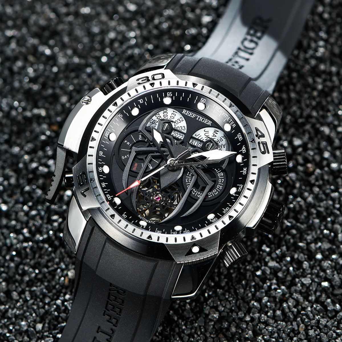 Black and silver watch with detailed face on a dark textured background