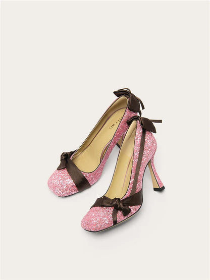 Pink glitter high heels with brown ribbons on a light gray background