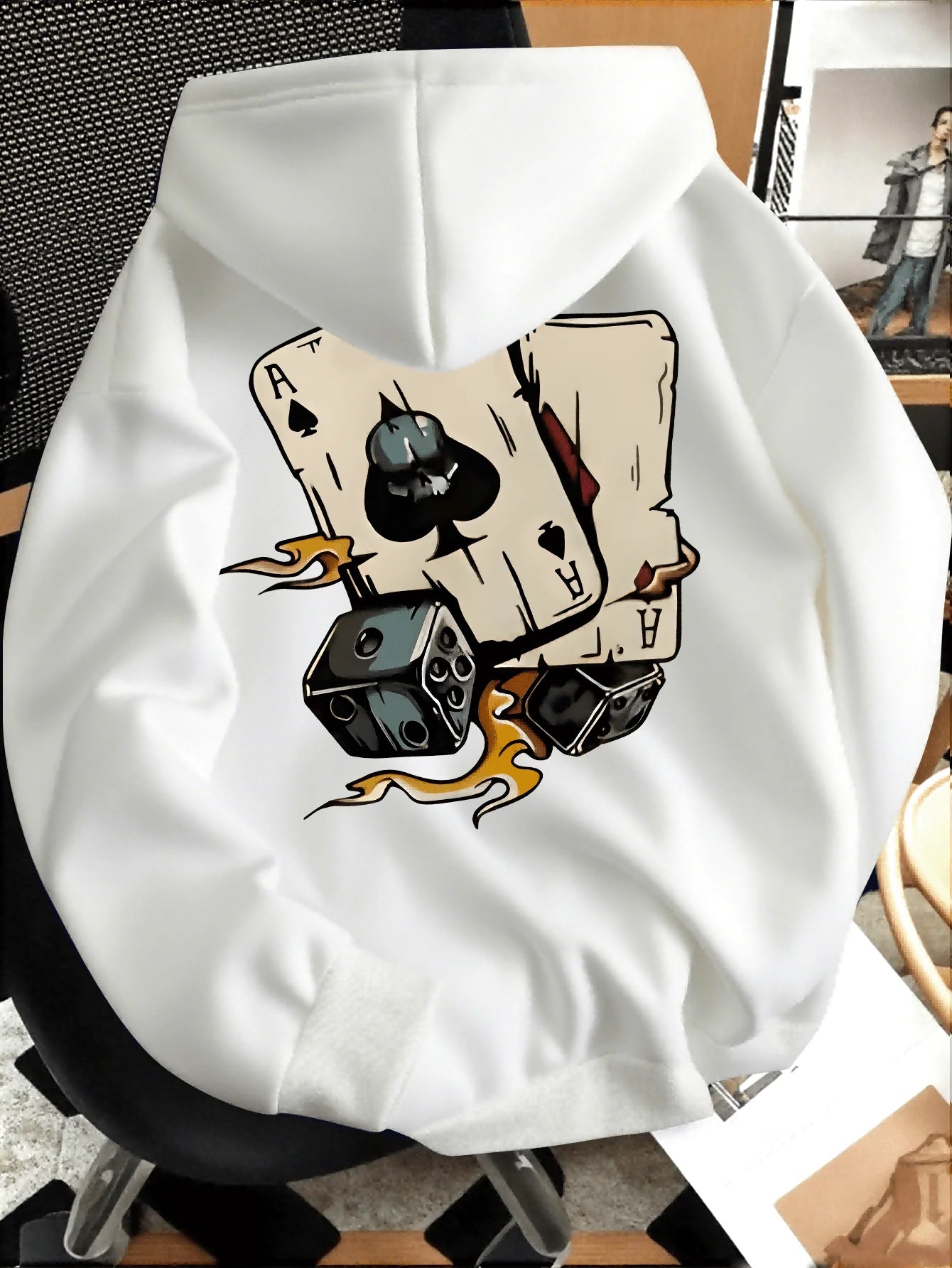 White hoodie with a graphic design of playing cards and dice on a chair.
