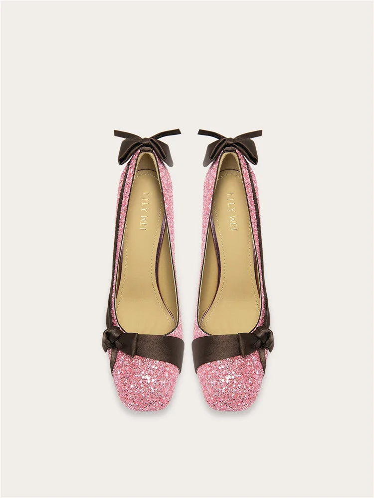 Pair of pink glittery shoes with brown bows on a white background
