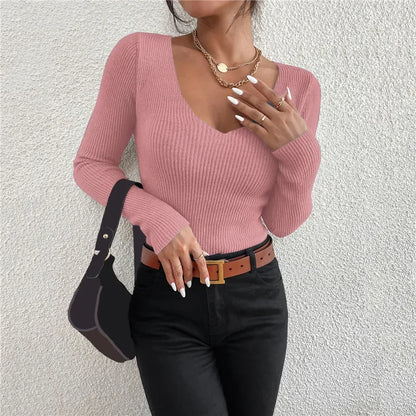 Person wearing a pink ribbed sweater and black pants against a light gray background