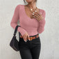 Person wearing a pink ribbed sweater and black pants against a light gray background