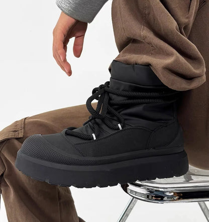 Black winter boot worn by a person sitting on a chair with a white background