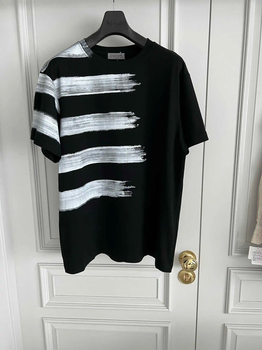 Black t-shirt with white brushstroke design on a hanger against a white door.