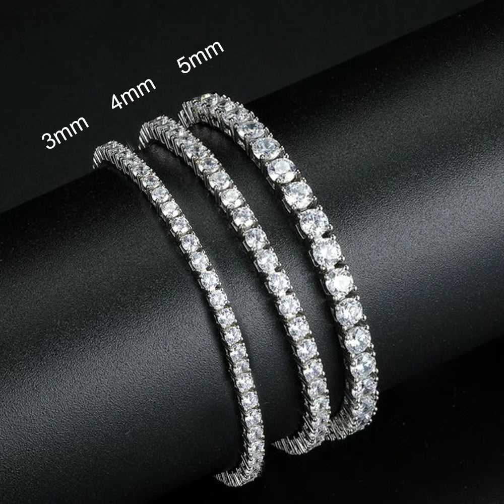 Three diamond tennis bracelets of different widths on a dark surface