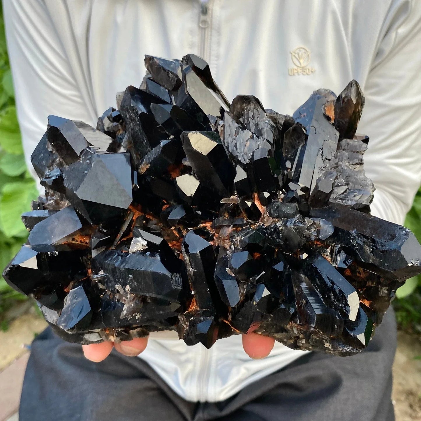 Person holding a large cluster of dark crystals with a blurred background