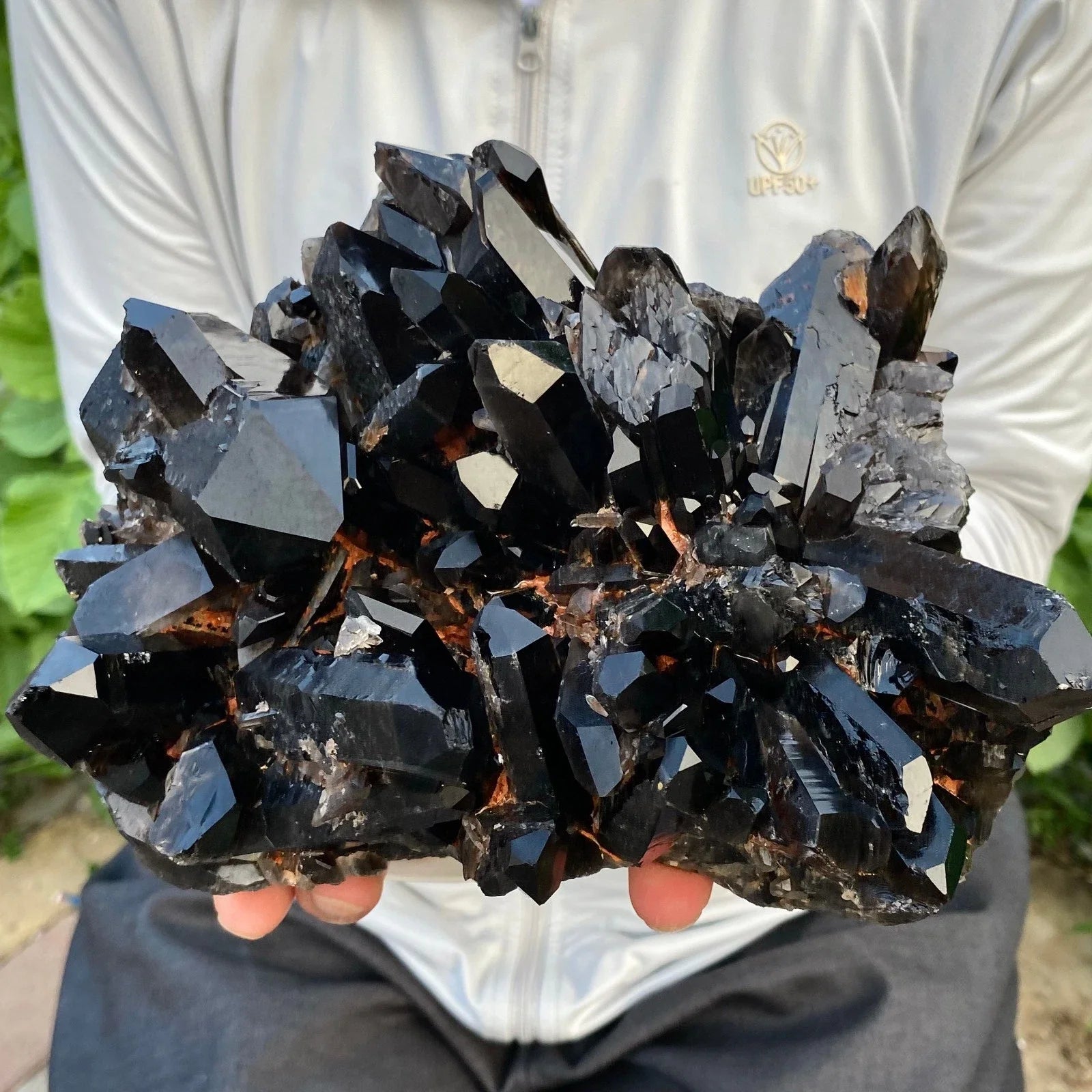 Person holding a large cluster of dark crystals with a blurred background