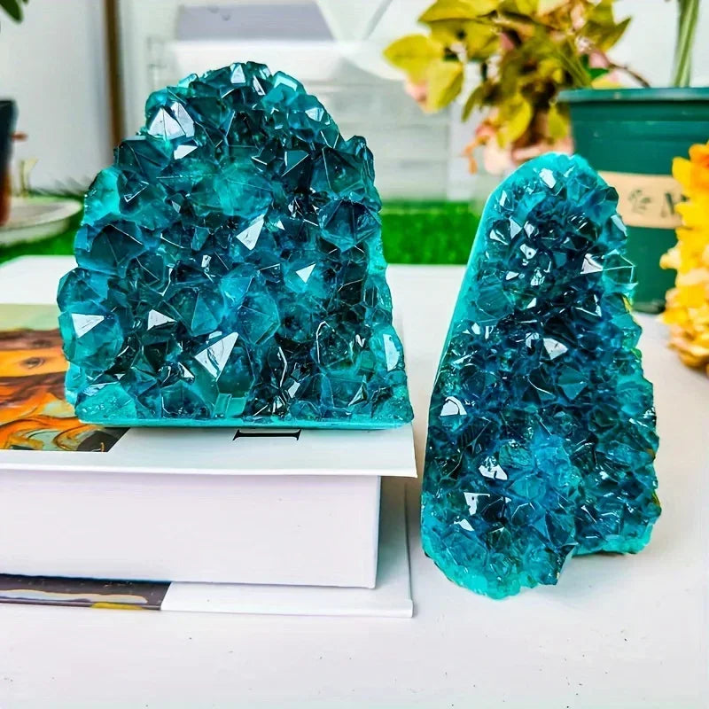 Two large turquoise crystal formations on a white surface with a blurred indoor background.