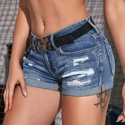 Person wearing ripped blue denim shorts with a blurred background