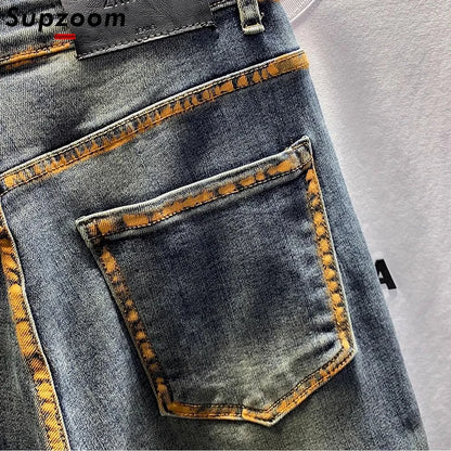 Close-up of a blue denim pocket with yellow stitching on a gray background