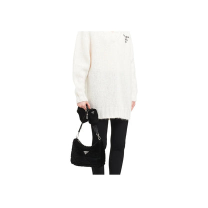 Person wearing a white sweater and black pants holding a black Prada handbag on a white background