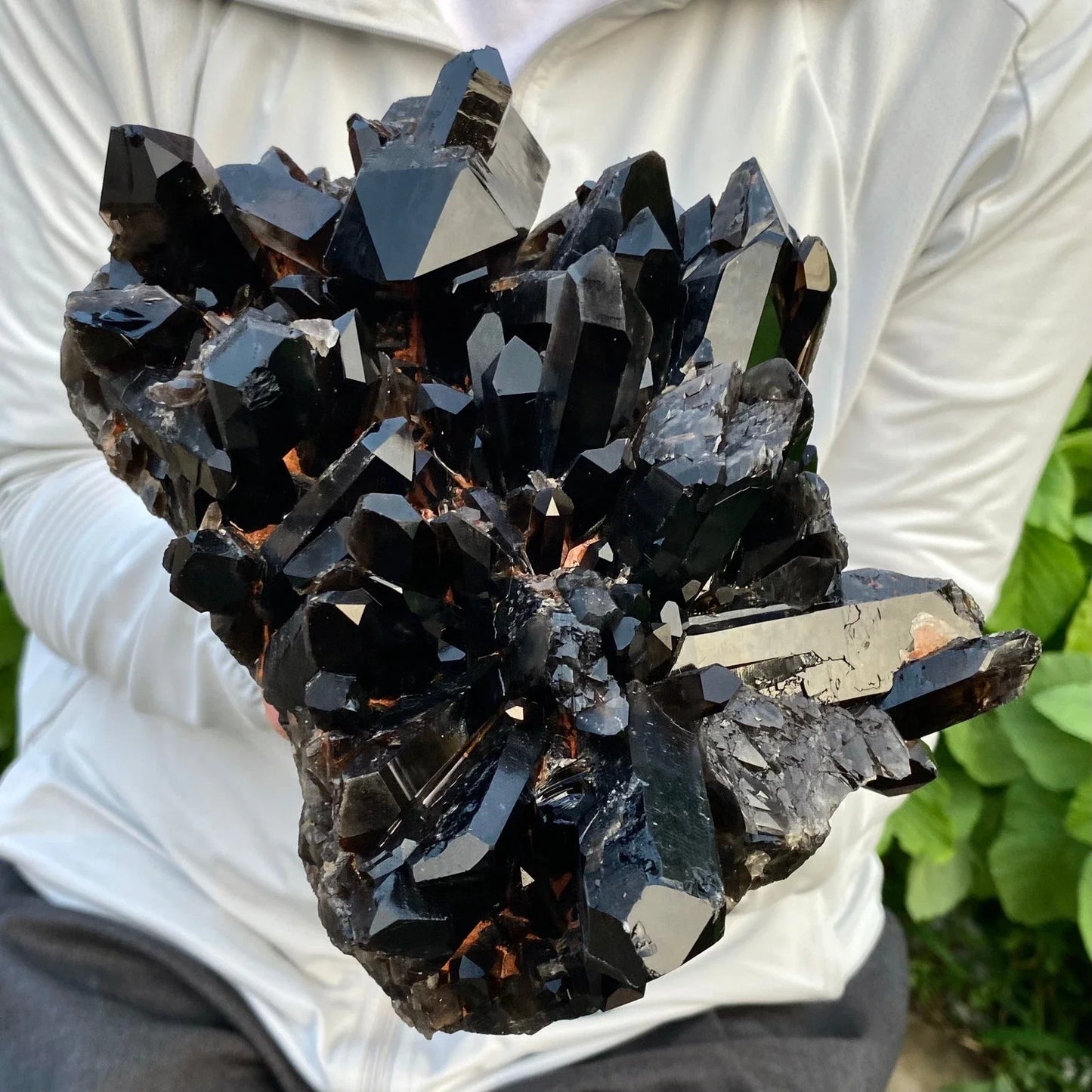 Black crystal cluster held by a person against a white background