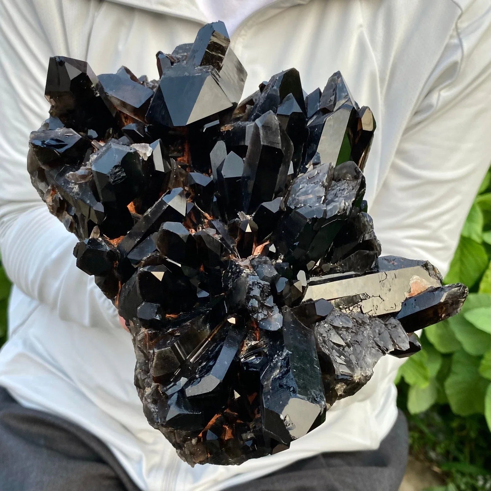 Black crystal cluster held by a person against a white background