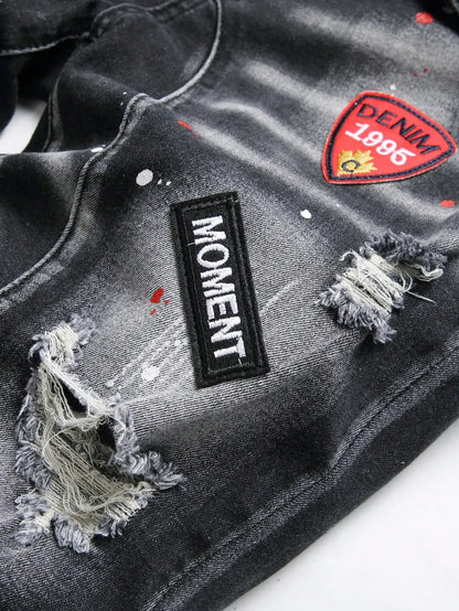 Black distressed denim jacket with 'Moment' and 'Denim 1896' patches on a white background