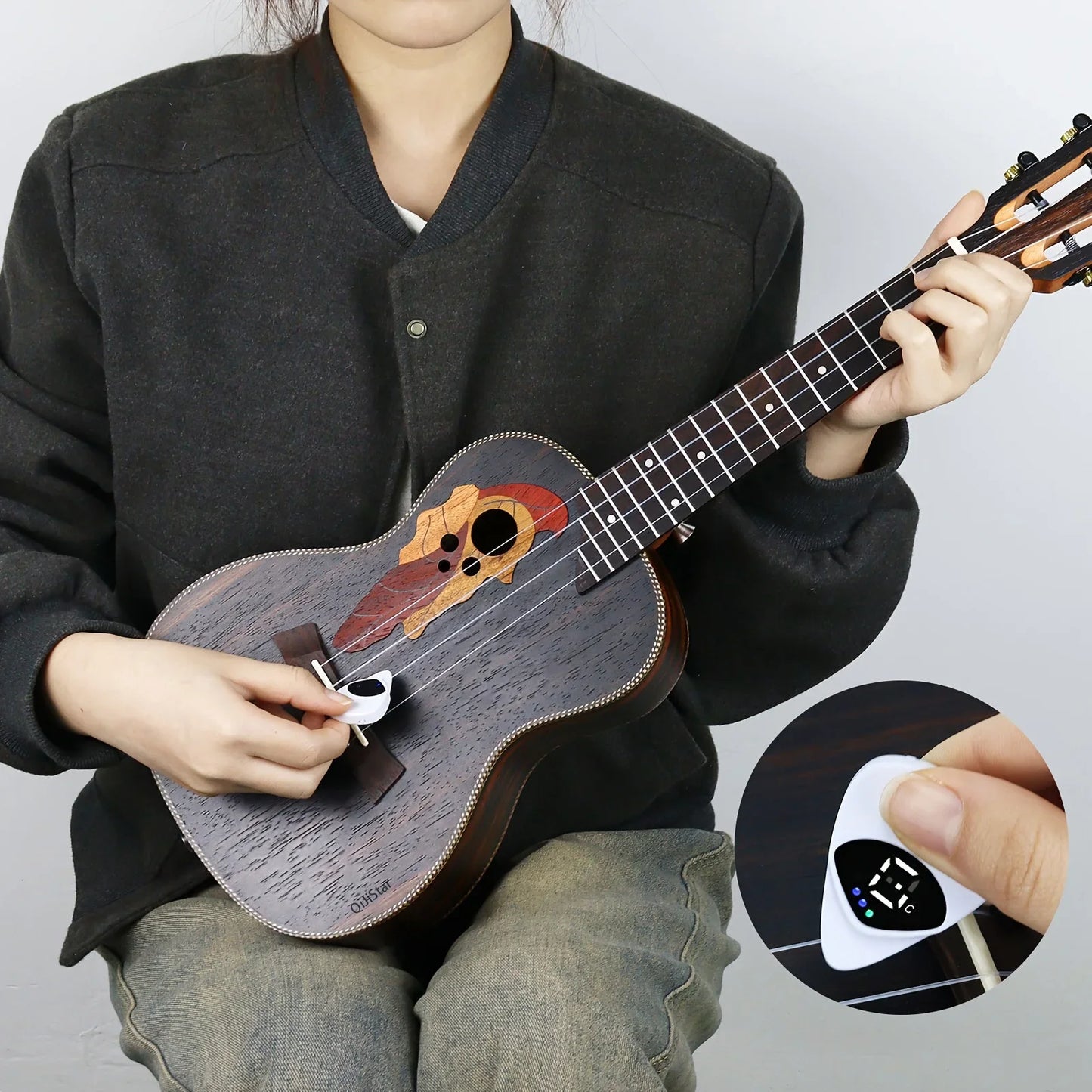 Person holding a ukulele with a close-up of a digital tuner on a gray background