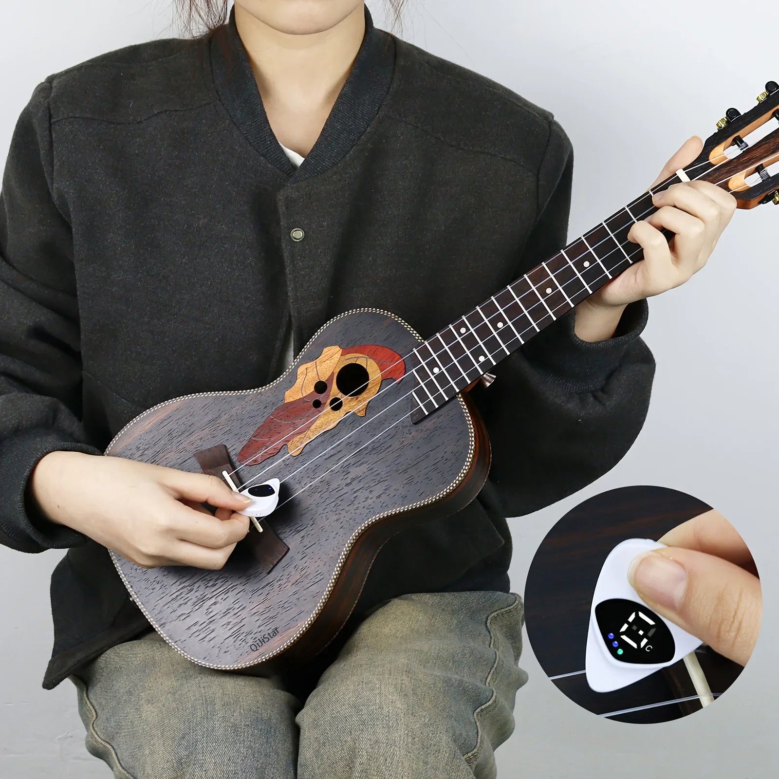 Person holding a ukulele with a close-up of a digital tuner on a gray background