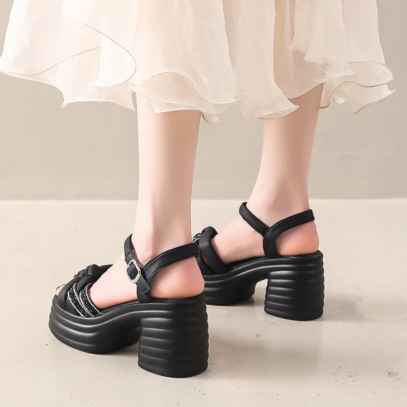 Black platform sandals worn with a light-colored skirt on a neutral background
