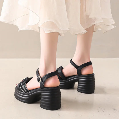 Black platform sandals worn with a light-colored skirt on a neutral background
