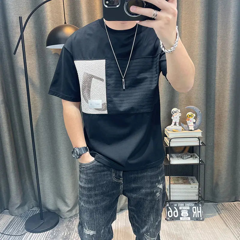 Person wearing a black t-shirt with a geometric design and jeans, taking a mirror selfie.