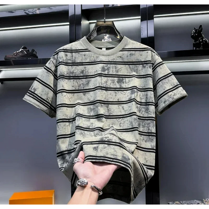 Striped t-shirt held by a hand with a blurred background