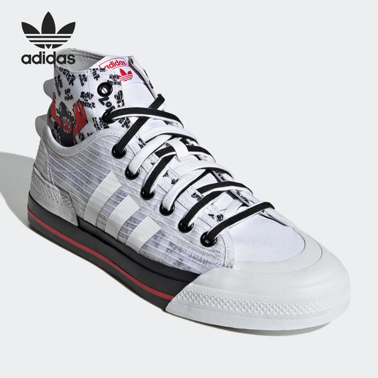 An Adidas x Travis Scott high-top sneaker in white, black, and red, featuring a patterned canvas upper, black laces, and a white rubber toe cap, shown on a light gray background with an Adidas logo overlay.