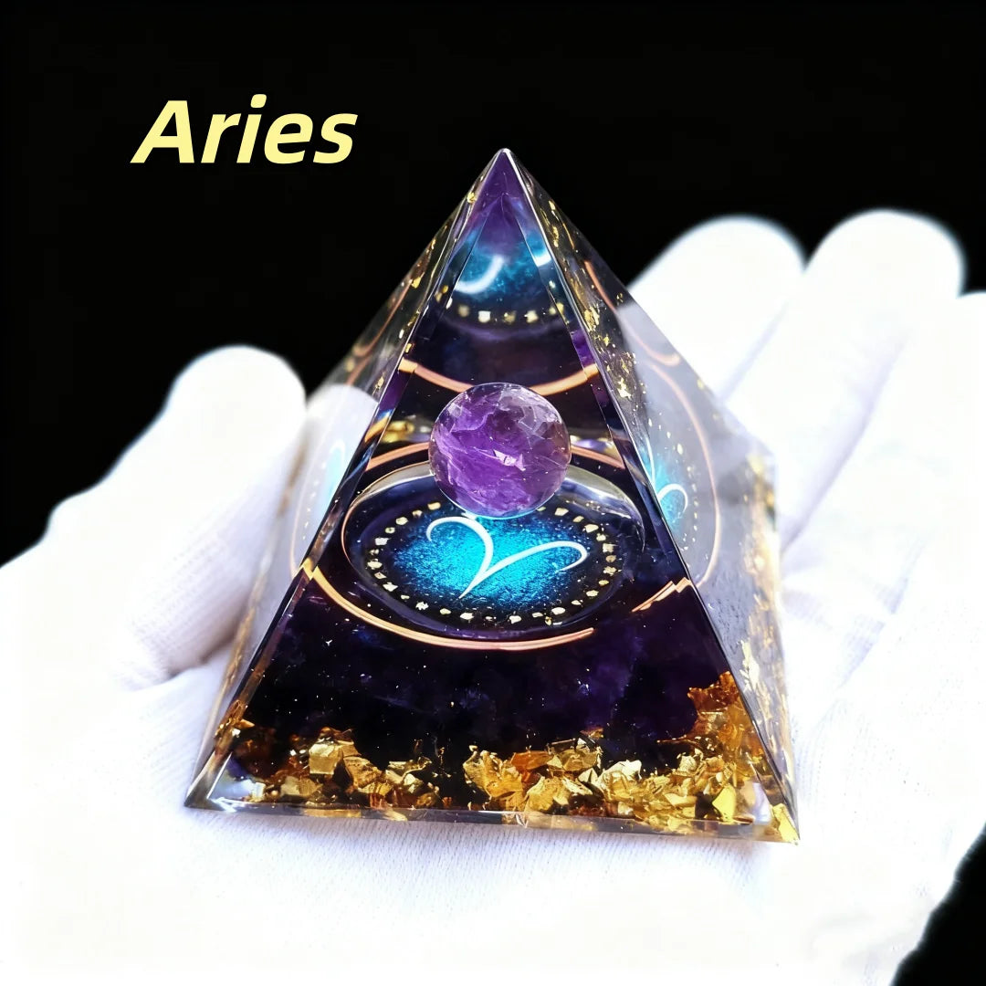Pyramid-shaped crystal with a purple sphere and gold flakes, labeled 'Aries', held by a gloved hand.