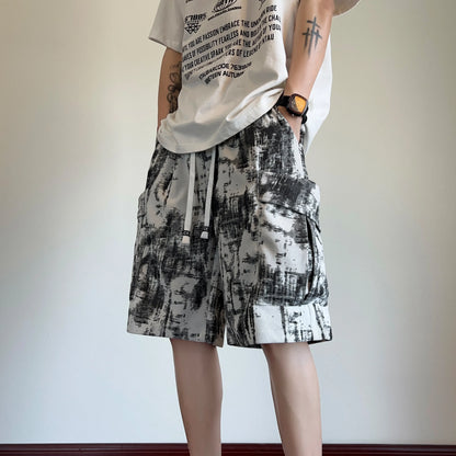 Person wearing a graphic t-shirt and patterned shorts against a plain background