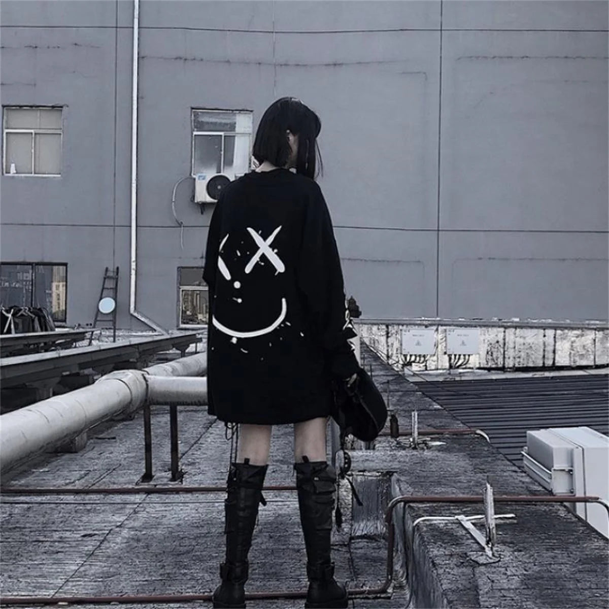 Person wearing a black hoodie with a unique design on a rooftop.