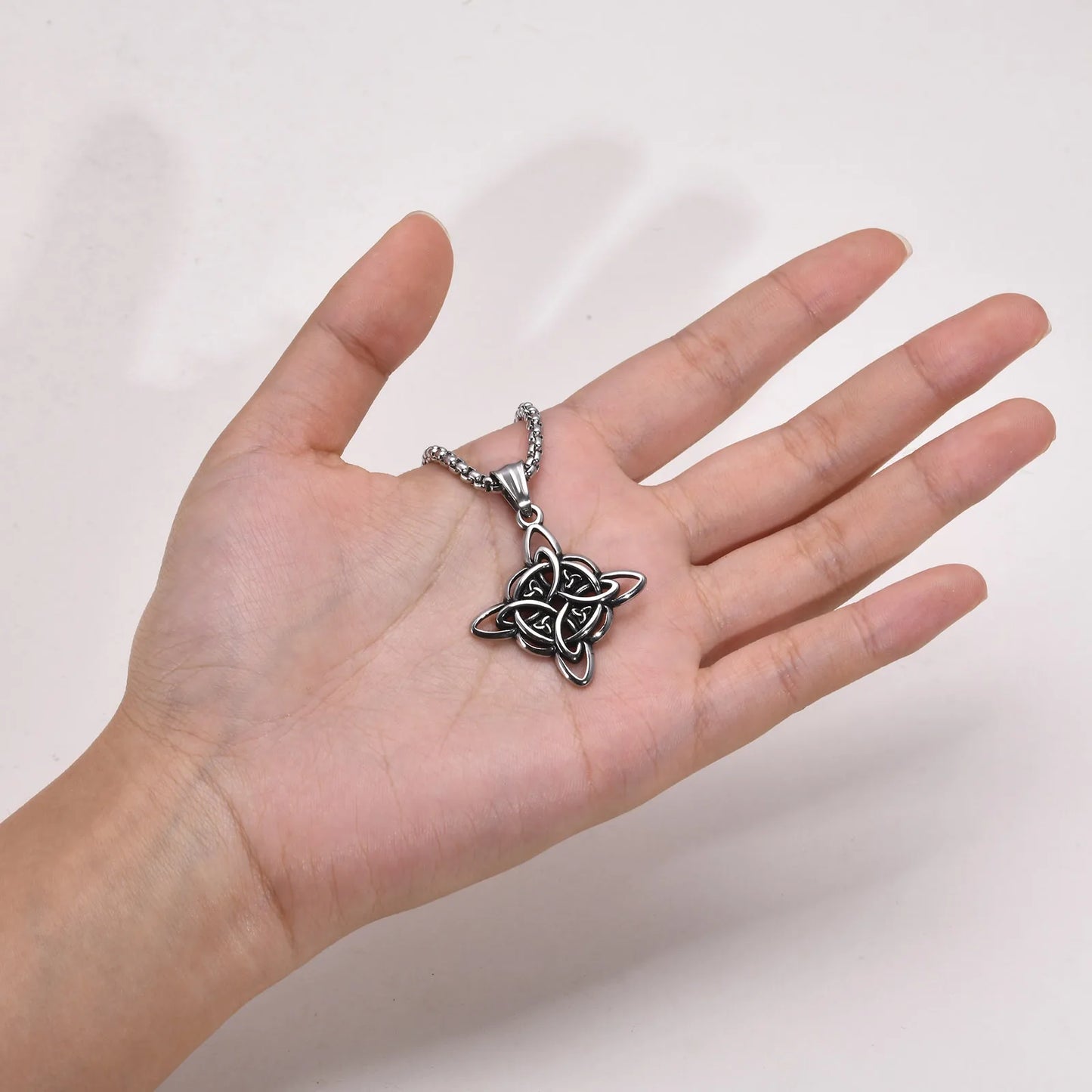 Vnox stainless steel Celtic knot amulet necklace held in hand to show pendant scale and Nordic Triquetra design.
