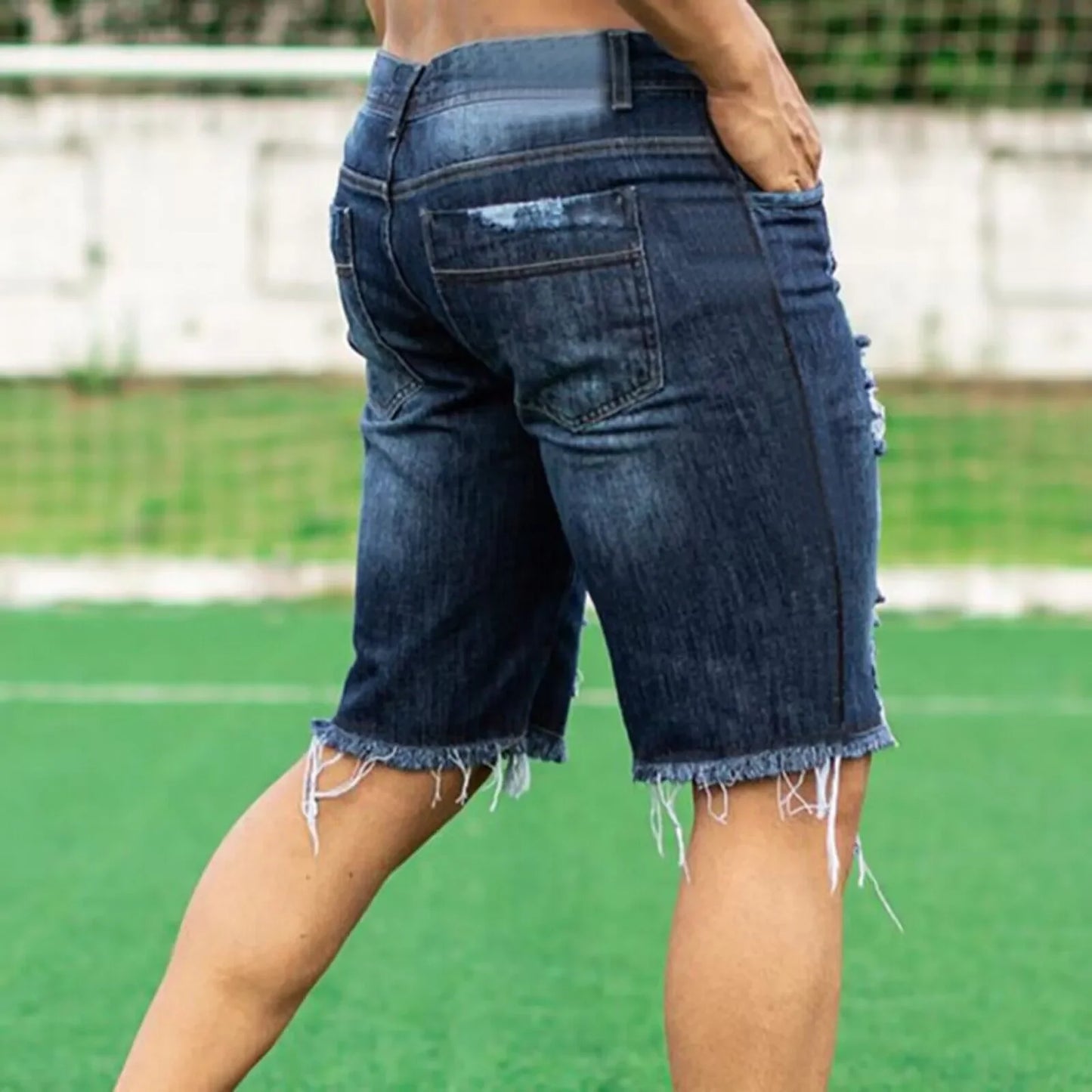 Person wearing blue denim shorts on a sports field